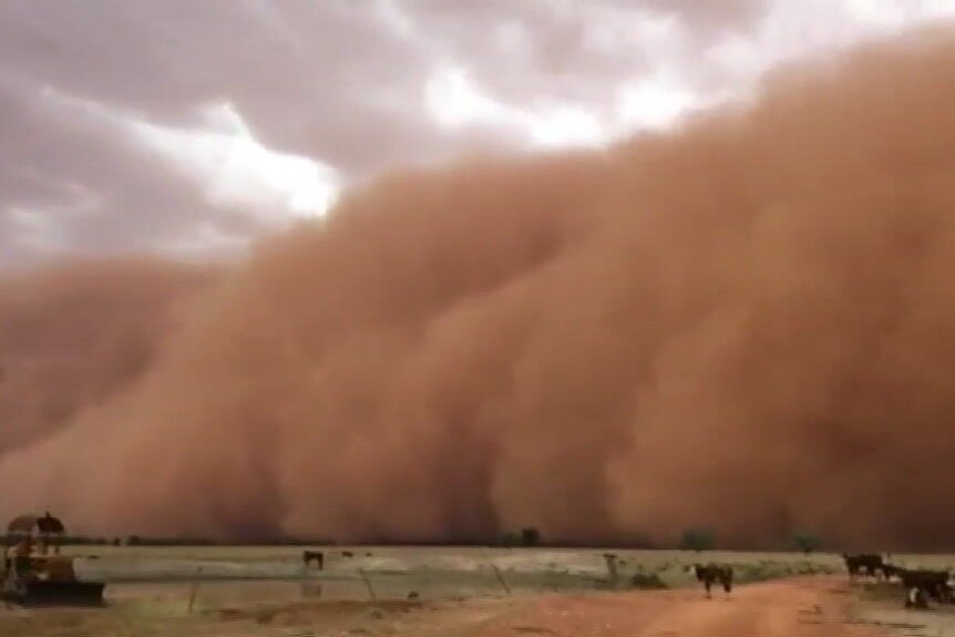 A large brown dust storm rolls across the landscape