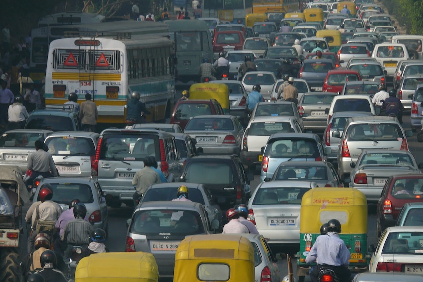Cars, motorbikes and buses are bumper to bumper in a traffic jam.