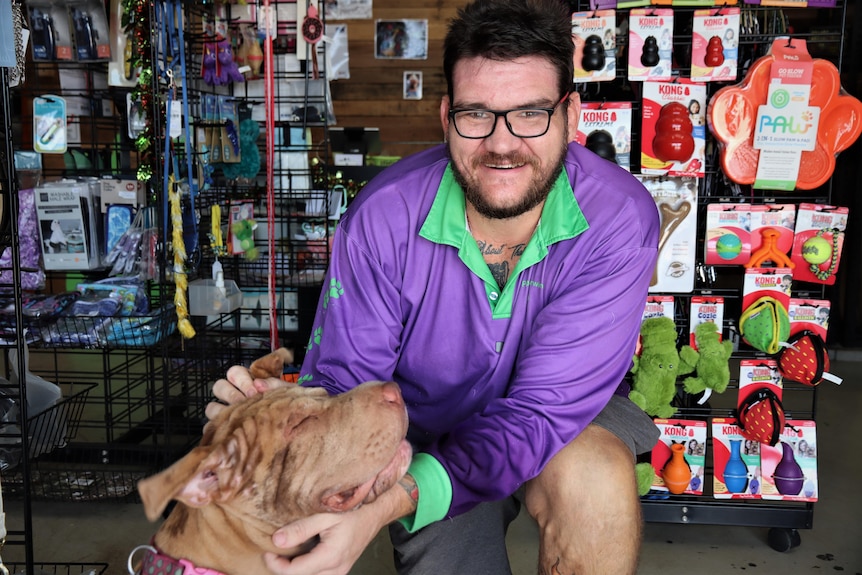 Portrait of a man patting a dog.