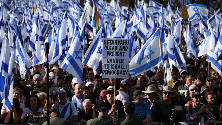 Man holds sig saying "Netanyahu clear and present danger to Israel democracy"