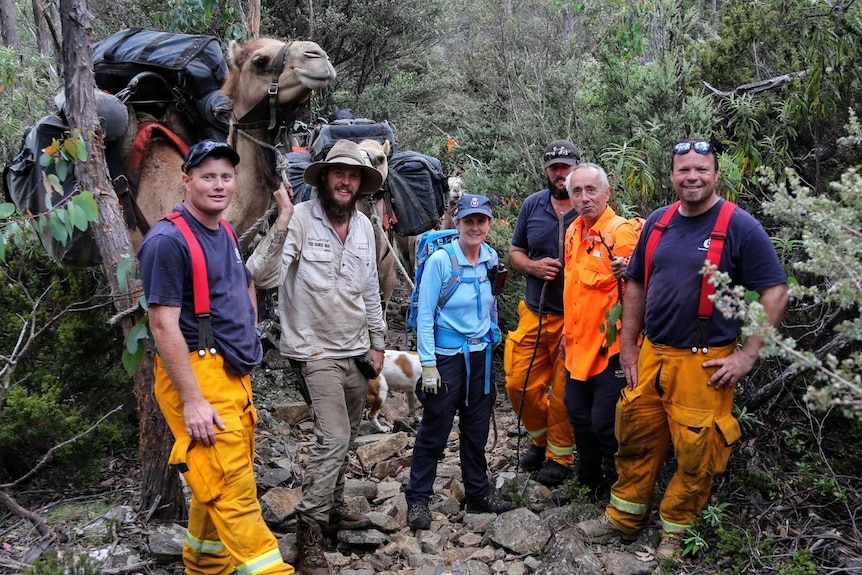 Volunteers from the Tasmania Fire Service and SES with John Elliott and his camels in bushland.