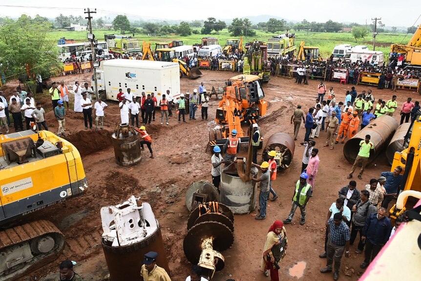 Workers gather to in India to save a boy trapped down a well.