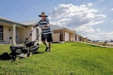 A man mowing the lawn outside a row of new houses