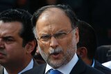 Ahsan Iqbal is surrounded by people as he speaks to media.