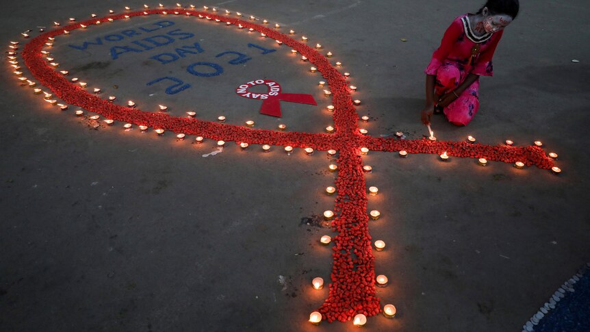 A girl lights earthen lamps in the shape of a red ribbon.  
