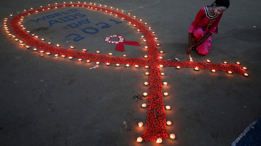 A girl lights earthen lamps in the shape of a red ribbon.  