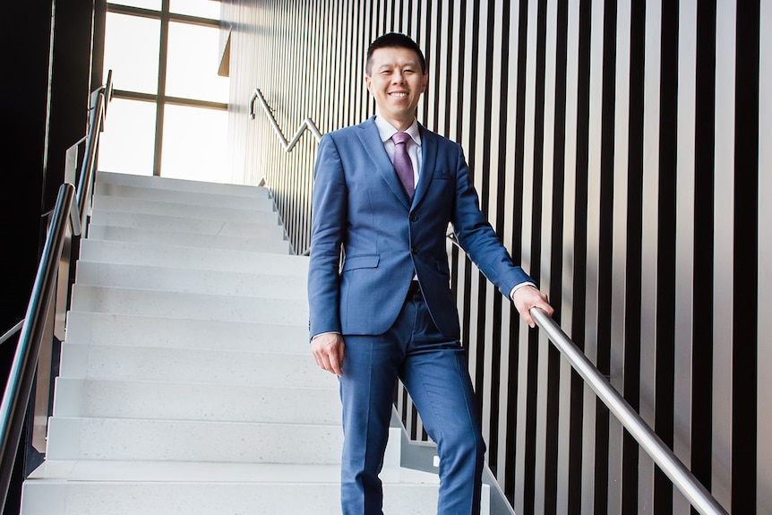 A man in suit and tie on staircase. He's smiling