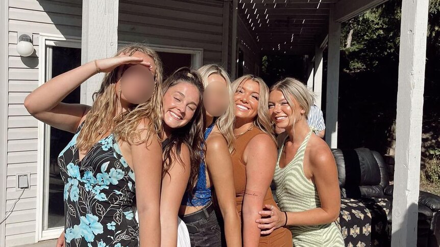 Five girls stand close to each other on a sunny porch