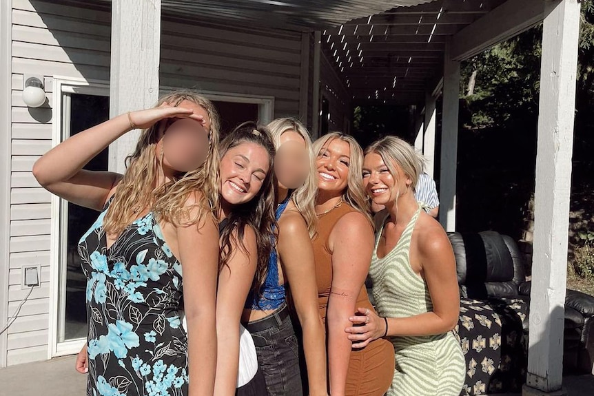 Five girls stand close to each other on a sunny porch