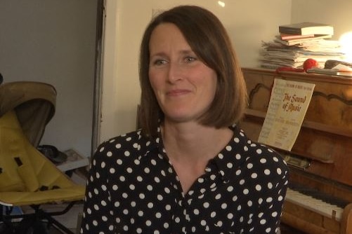 A lady in a polka dot shirt and reddish-brown hair looks at the camera
