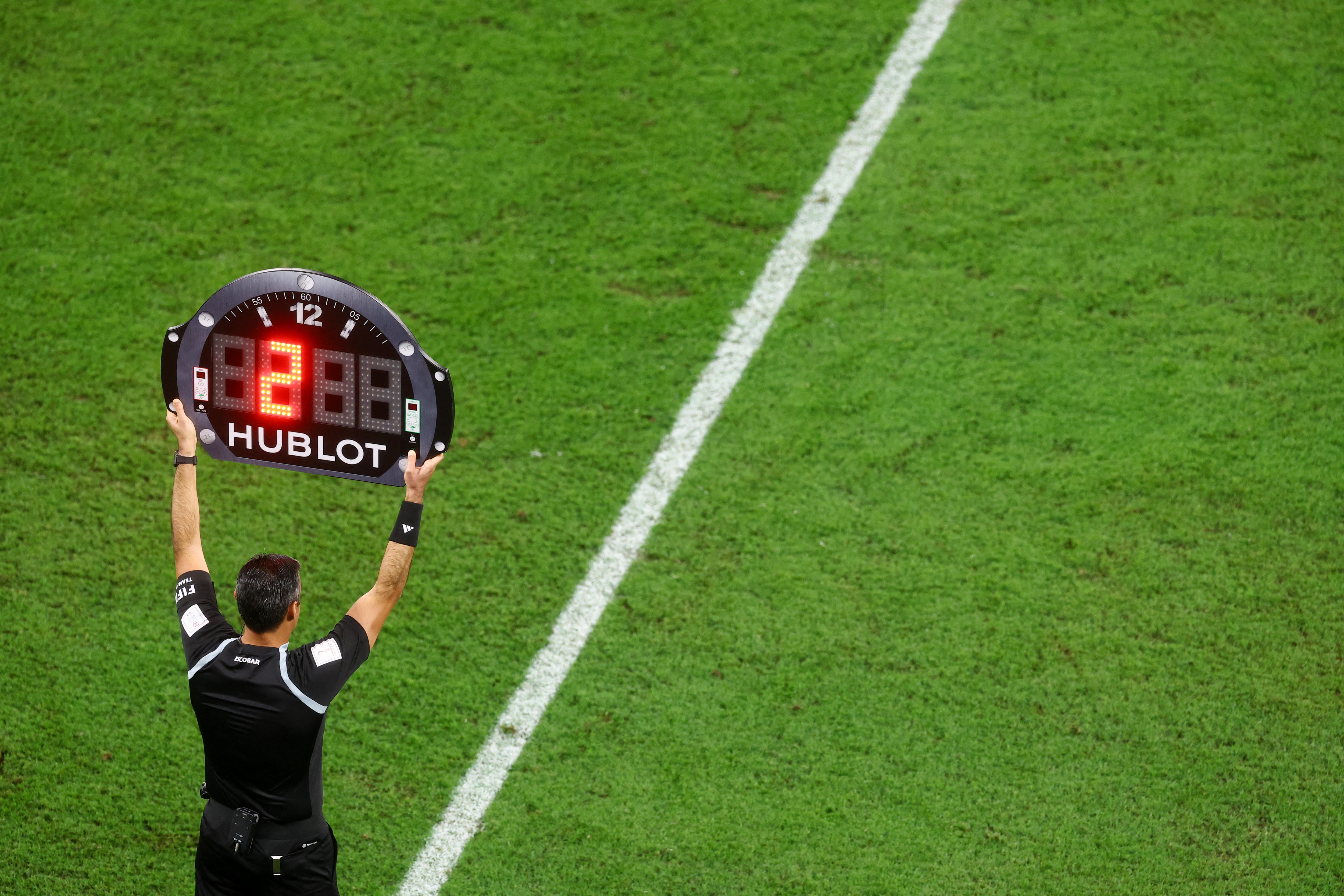 A referee holds up a sign that resembles a watch face showing 2 lit up.