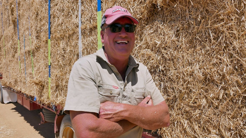 Scaddan farmer Gavin Egan laughing as he stands in front of a truck loaded with hay bales.
