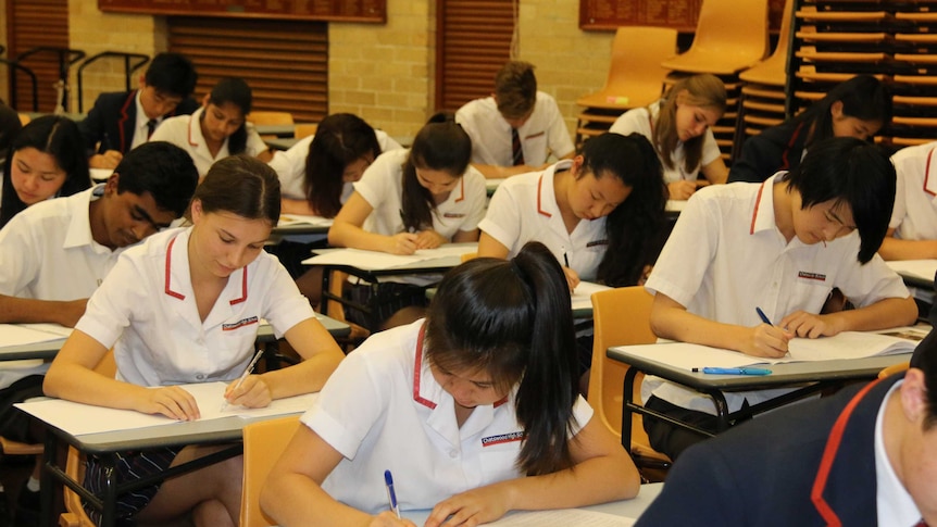 Students sit at a desk and write during exams.