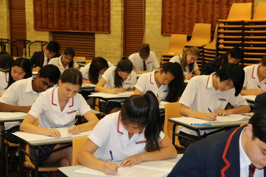 Students sit at a desk and write during exams.