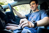 a young man holds a gear stick inside a car