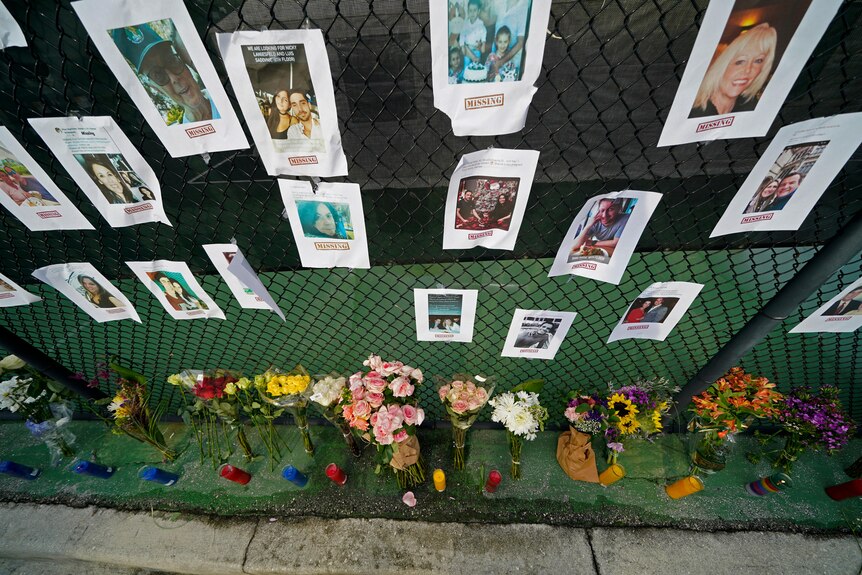A makeshift memorial bears photos of some of the missing people that hangs from a fence.