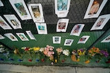 A makeshift memorial bears photos of some of the missing people that hangs from a fence.