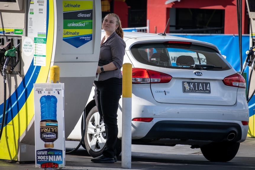 A woman at a petrol pump with her car in Brisbane.