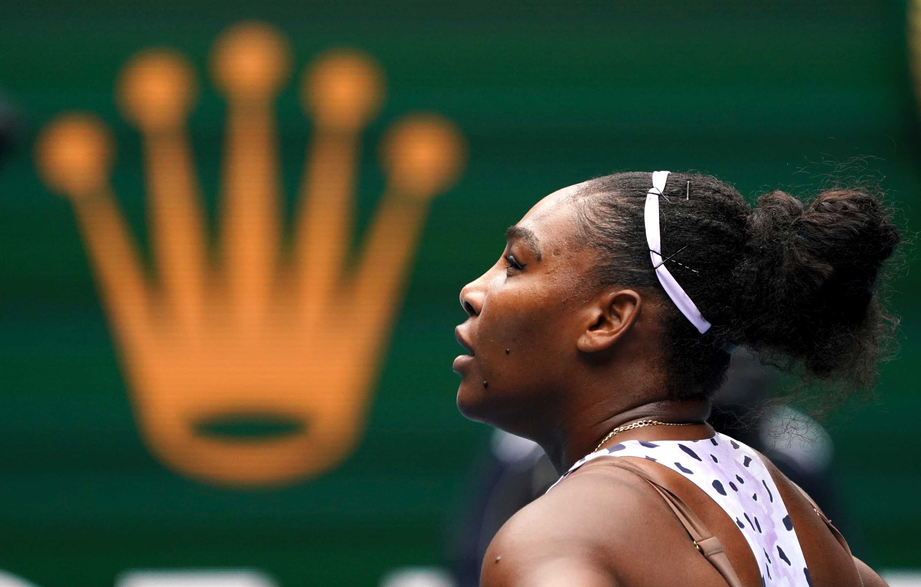 Serena Williams looks up with a crown appearing in the background, in front of her face