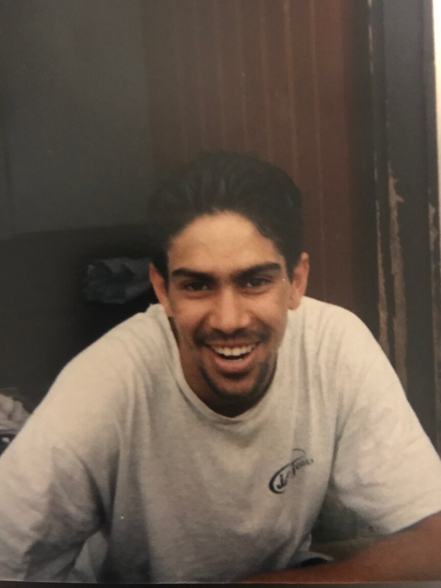 A young Indigenous man in a white shirt, smiling. 