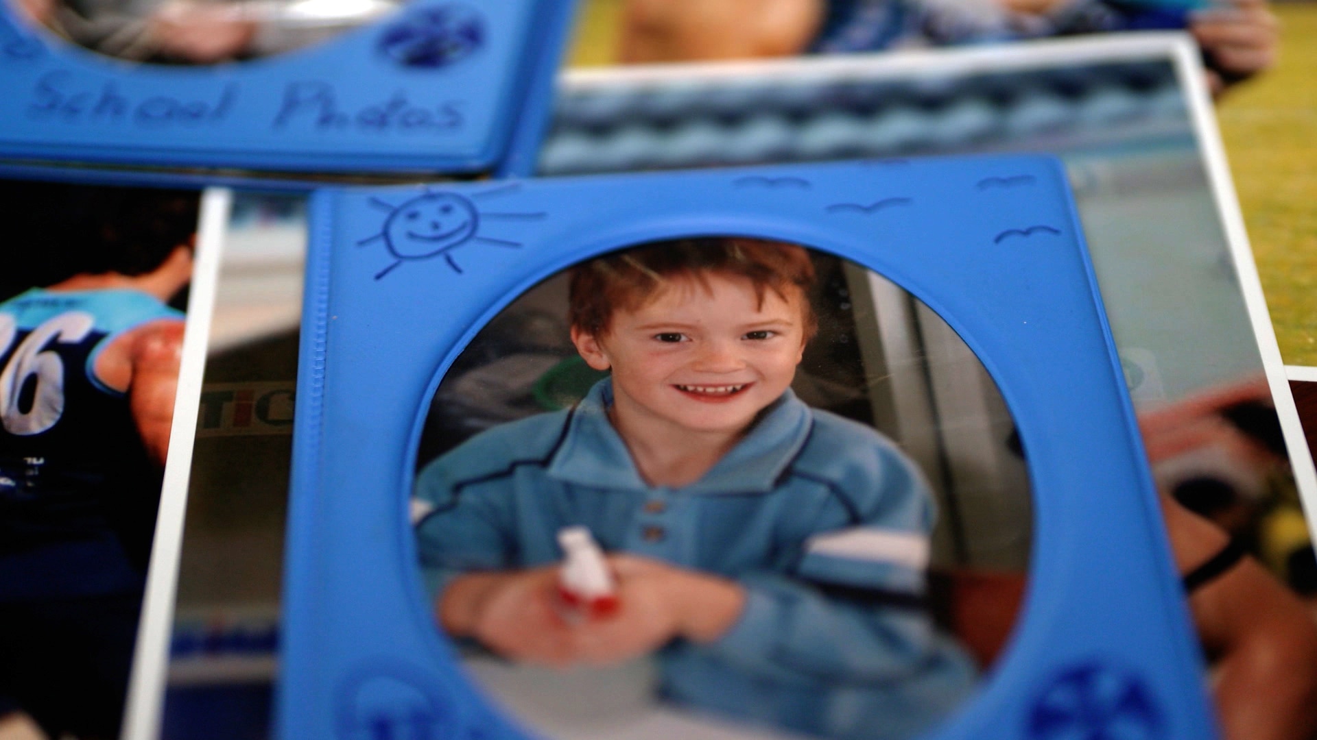 A photo in a frame of a smiling young boy. Underneath it are other photos.