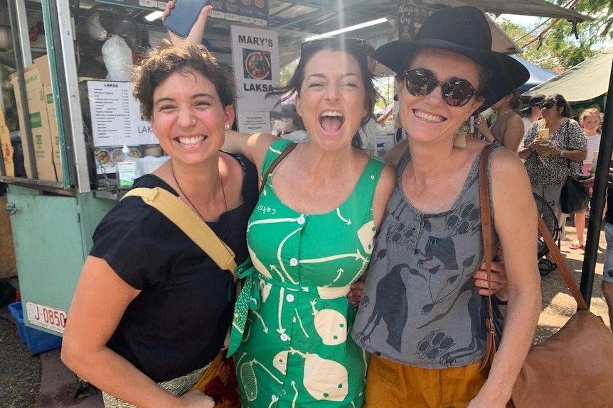 Three women outside a market laksa street food van.