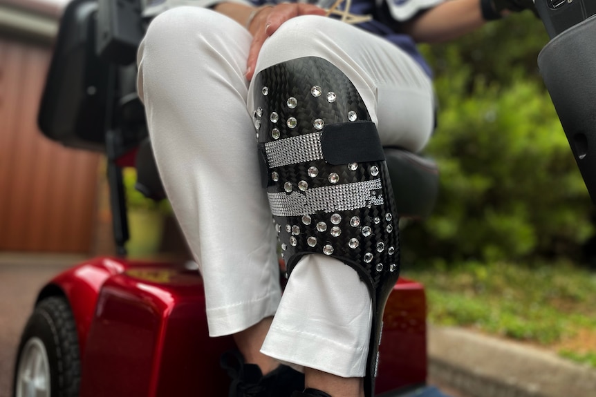 A woman's legs, one is in a leg brace that is bedazzled with diamonte