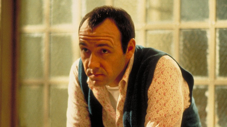 Kevin Spacey's character sits with his arms on his knees