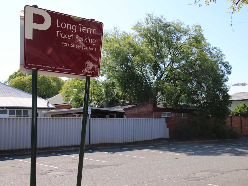 An empty suburban car park bounded by houses.