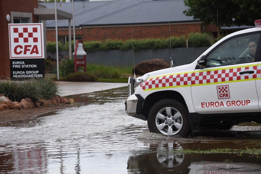 CFA Volunteers drive into the fire station - the driveway is slowly seeing floodwaters rise.
