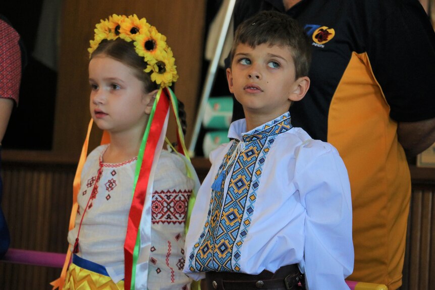 A young boy and girl dressed in traditional Ukrainian clothing and looking away from the camera. 