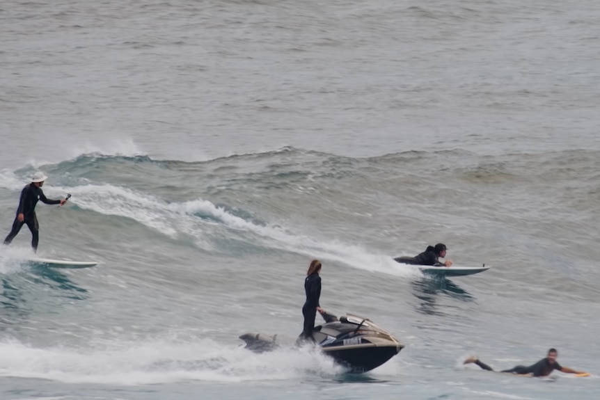 Barney Miller laying down on the surfboard on a wave