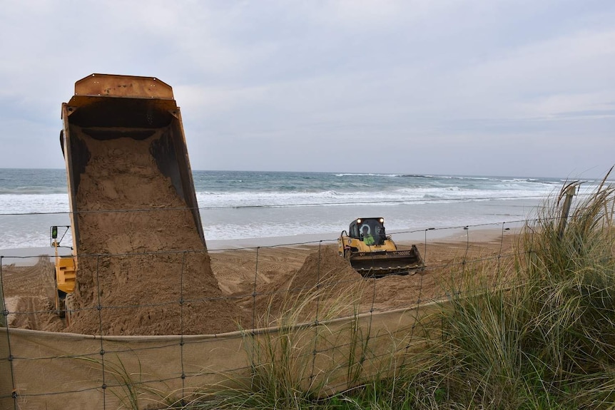 A truck and earth mover move sand at Marengo beach on the Great Ocean Road.