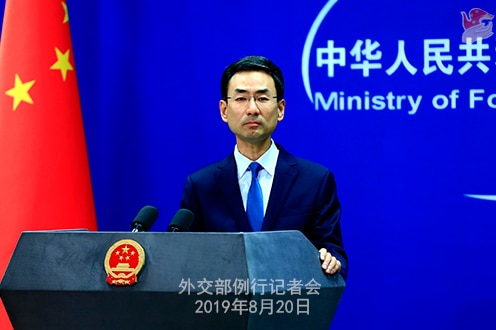 China's foreign ministry spokesperson Geng Shuang stands in front of a podium and next to a Chinese flag.