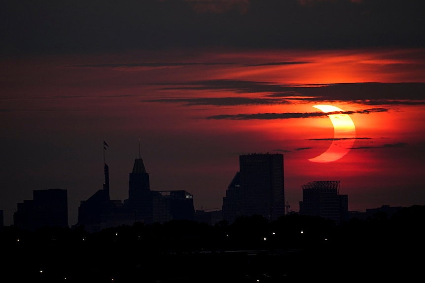 A partial solar eclipse rises over the Baltimore