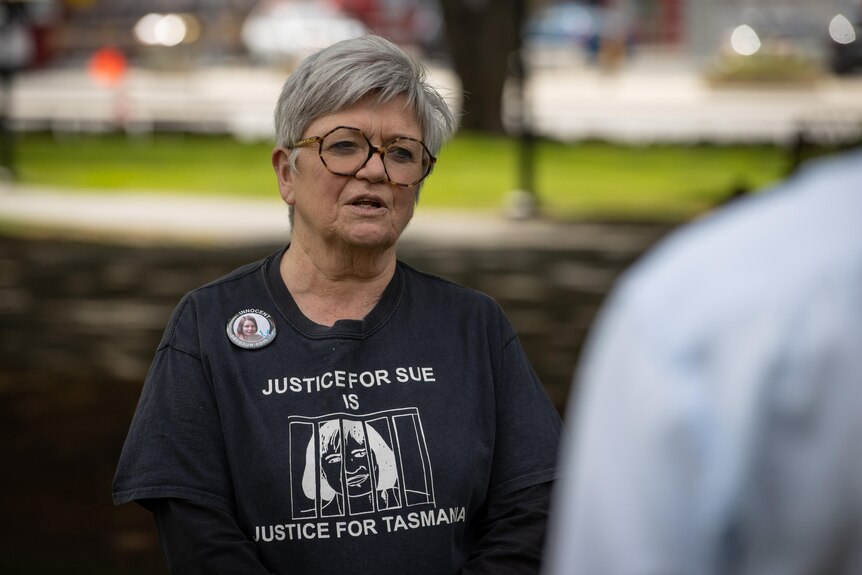  A woman with silver hair wears a t-shirt with the words: Justice for Sue - Justice for Tasmania