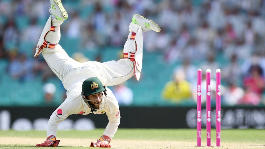 Matthew Wade performs a handstand on a cricket pitch.