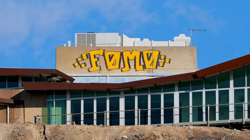 The word FOMO spray painted with yellow paint on a building at the top of the Line of Lode in Broken Hill.
