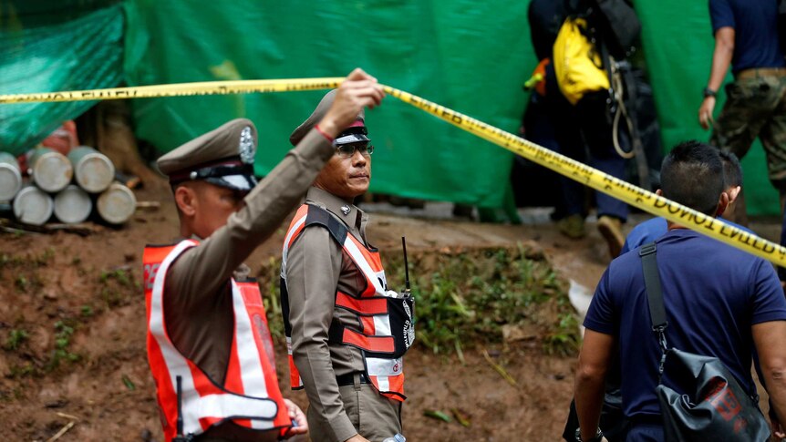 A police officer raises tape at the cave complex