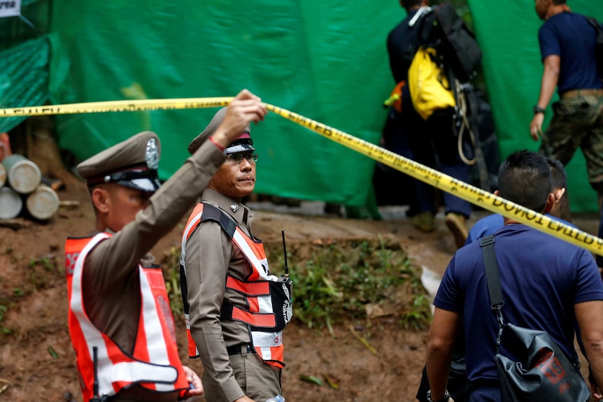 A police officer raises tape at the cave complex