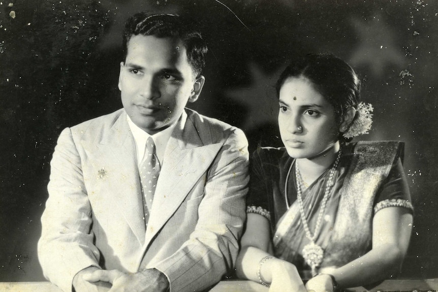 An old black and white image of a young man wearing a suit and a woman wearing a sari.