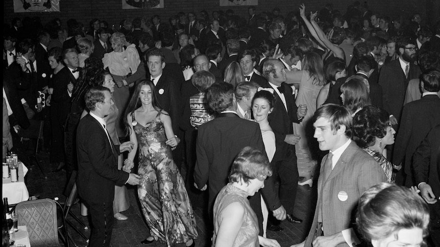 Black and white photograph of people in formal wear dancing in a ballroom.
