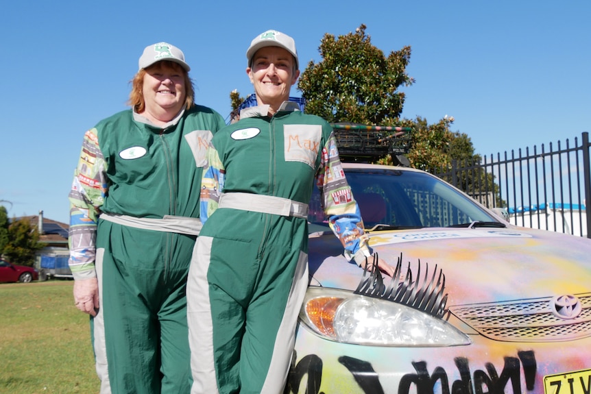Allison and Maxine stand in front of their graffiti painted Toyota Camry with fake eyelashes. 