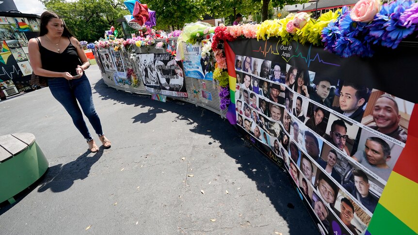 A visitor looks over a display with the photos and names of the 49 victims that died at the Pulse nightclub memorial.