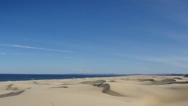 Undulating sand with ocean in the background.