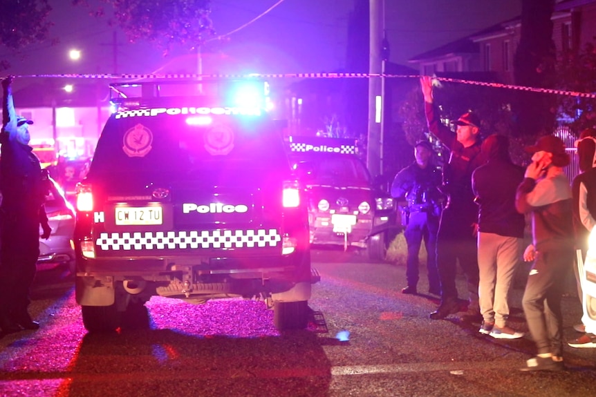 A police car with officers standing around and other people