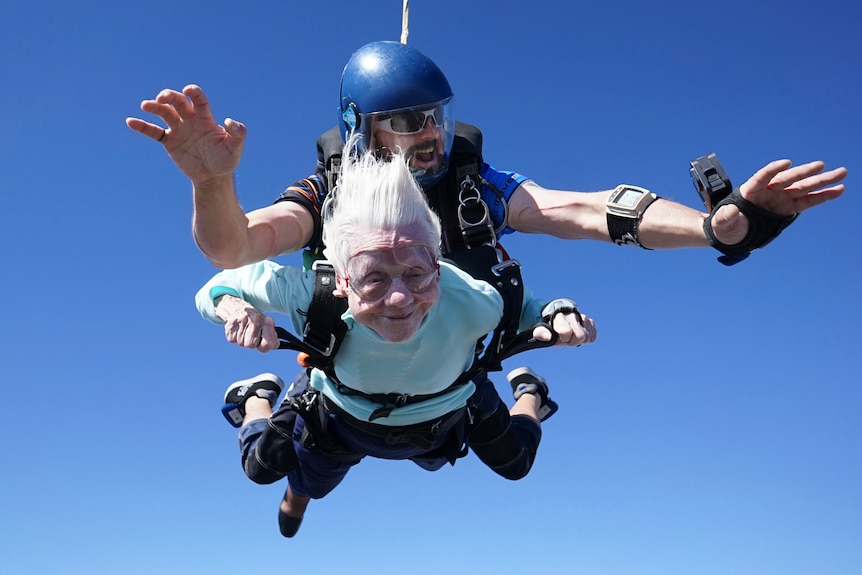 An elderly woman skydiving with a man. 