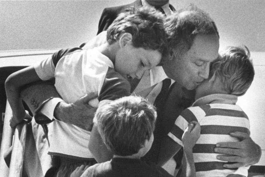 A black and white photo of Pierre Trudeau embracing his three sons