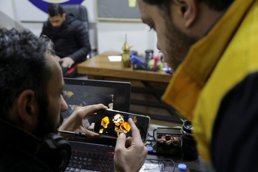 Two rescuers looks at footage of a rescue on a mobile phone. 