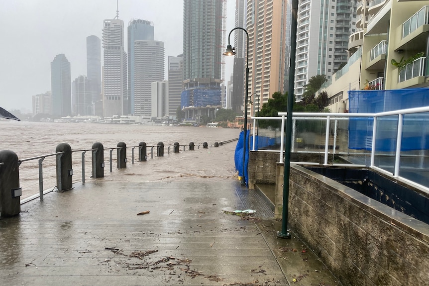 Water washes onto a footpath from the Brisbane River.